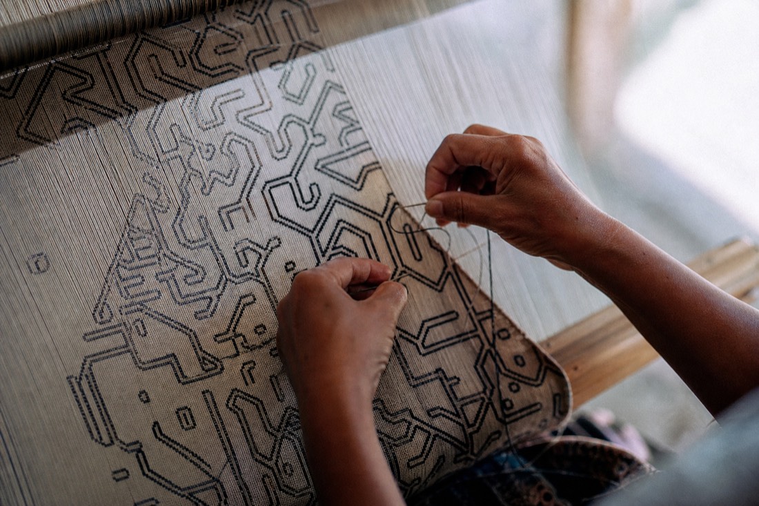 Shipibo-style geometric textile patterns being woven by hand, close-up on the cloth, Ucayali region