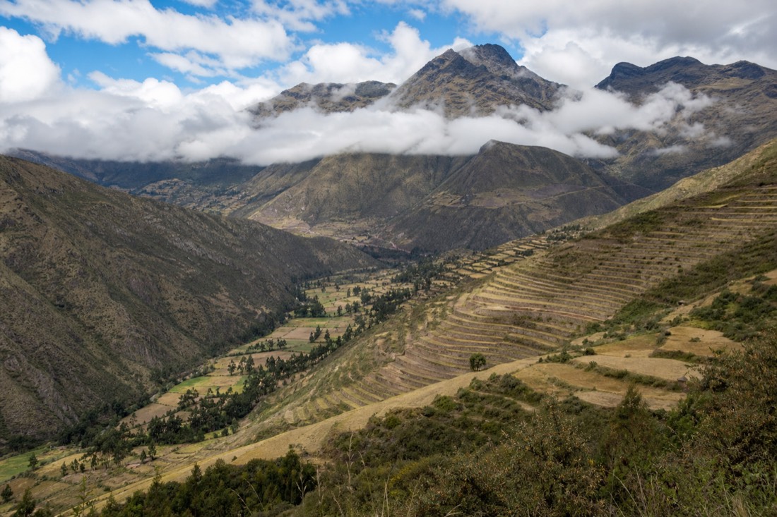 High Andean valley with terraced slopes and clouds low over the peaks near Cusco