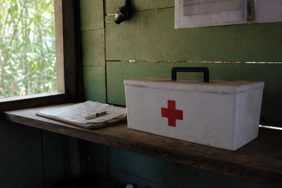 First aid kit and clipboard on a wooden shelf in a simple retreat office