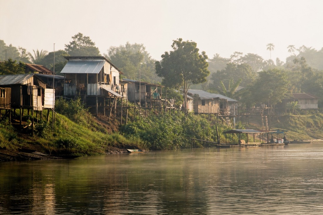 River village at the edge of the Amazon with wooden houses on stilts in morning haze