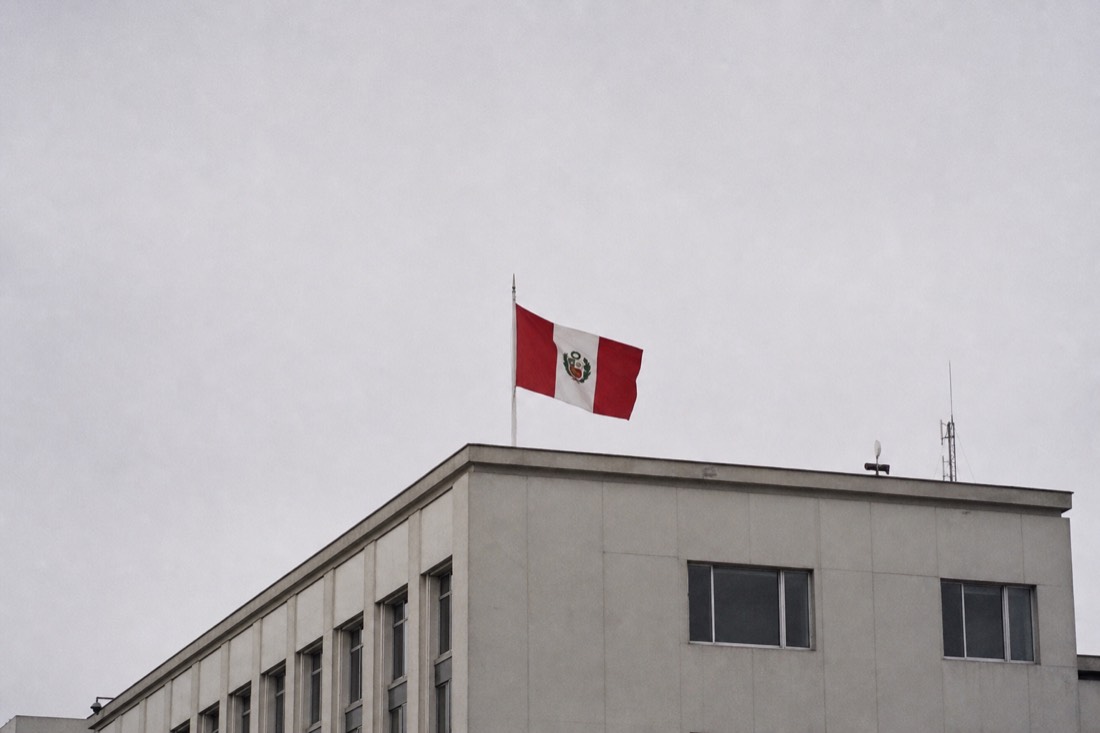 Peruvian flag on a government building facade in Lima under a grey coastal sky