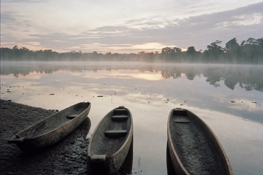 Wooden dugout canoes resting on the calm surface of Yarinacocha lake at dawn near Pucallpa