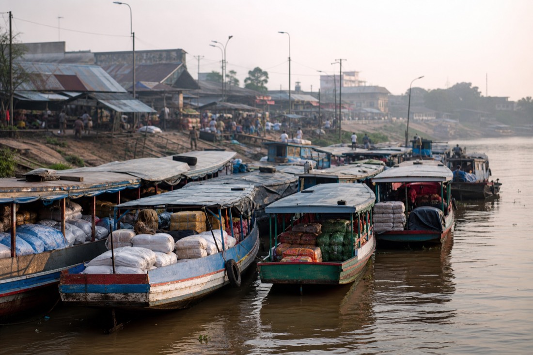 Long wooden riverboats loaded with cargo moored along the busy Iquitos riverfront in morning haze