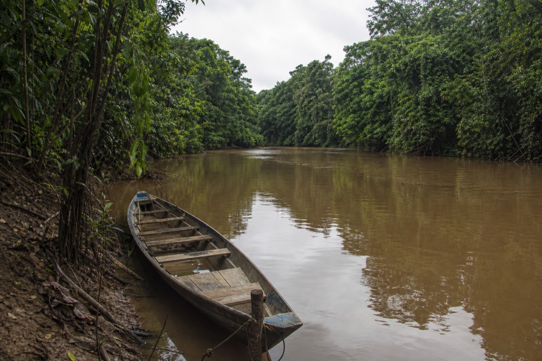 Narrow wooden boat moored at a quiet fork where two jungle rivers meet near Iquitos
