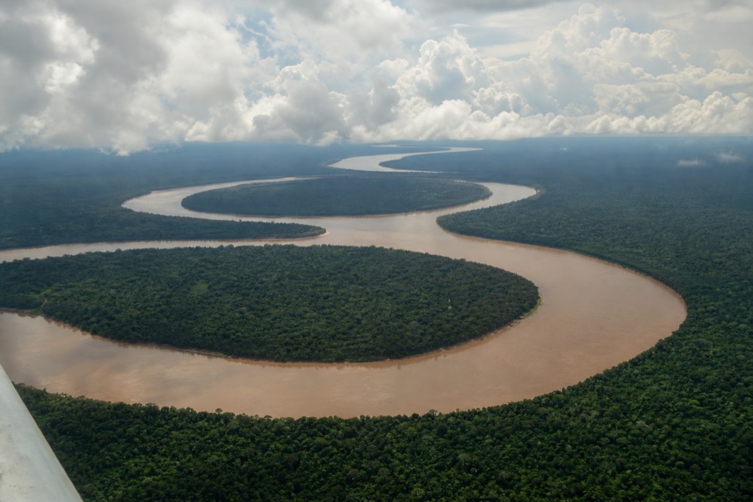 Wide aerial view of the Amazon river winding through rainforest near Iquitos under afternoon clouds